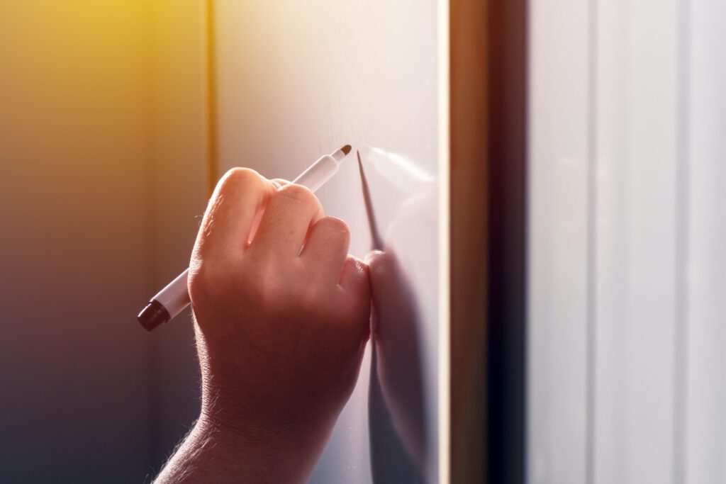 School teacher writing on classroom whiteboard